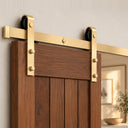 Light Gold single barn door hardware kit with full rail and two hangers on a walnut door, angled view