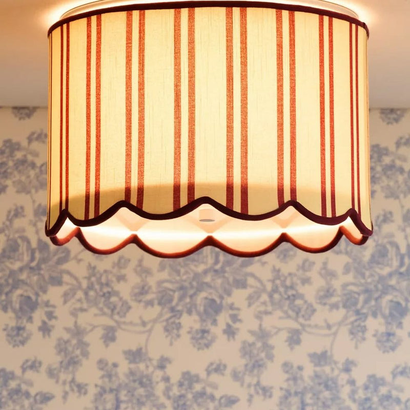 Scalloped striped lampshade against blue toile wallpaper