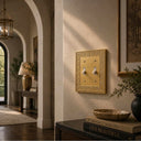 Laurel Brushed Gold 2-gang toggle switch plate on a wall beside an arched entryway