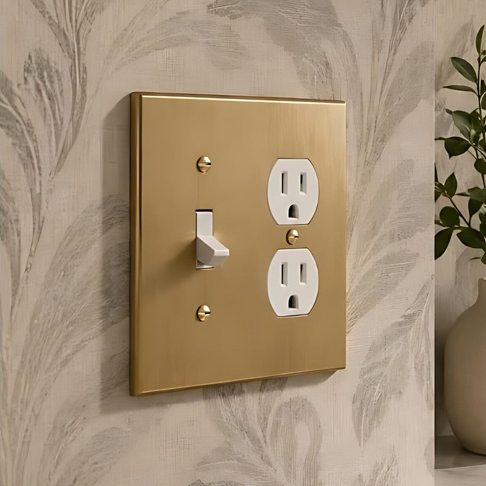 Forge Brushed Gold toggle and duplex combination plate on a patterned wall.