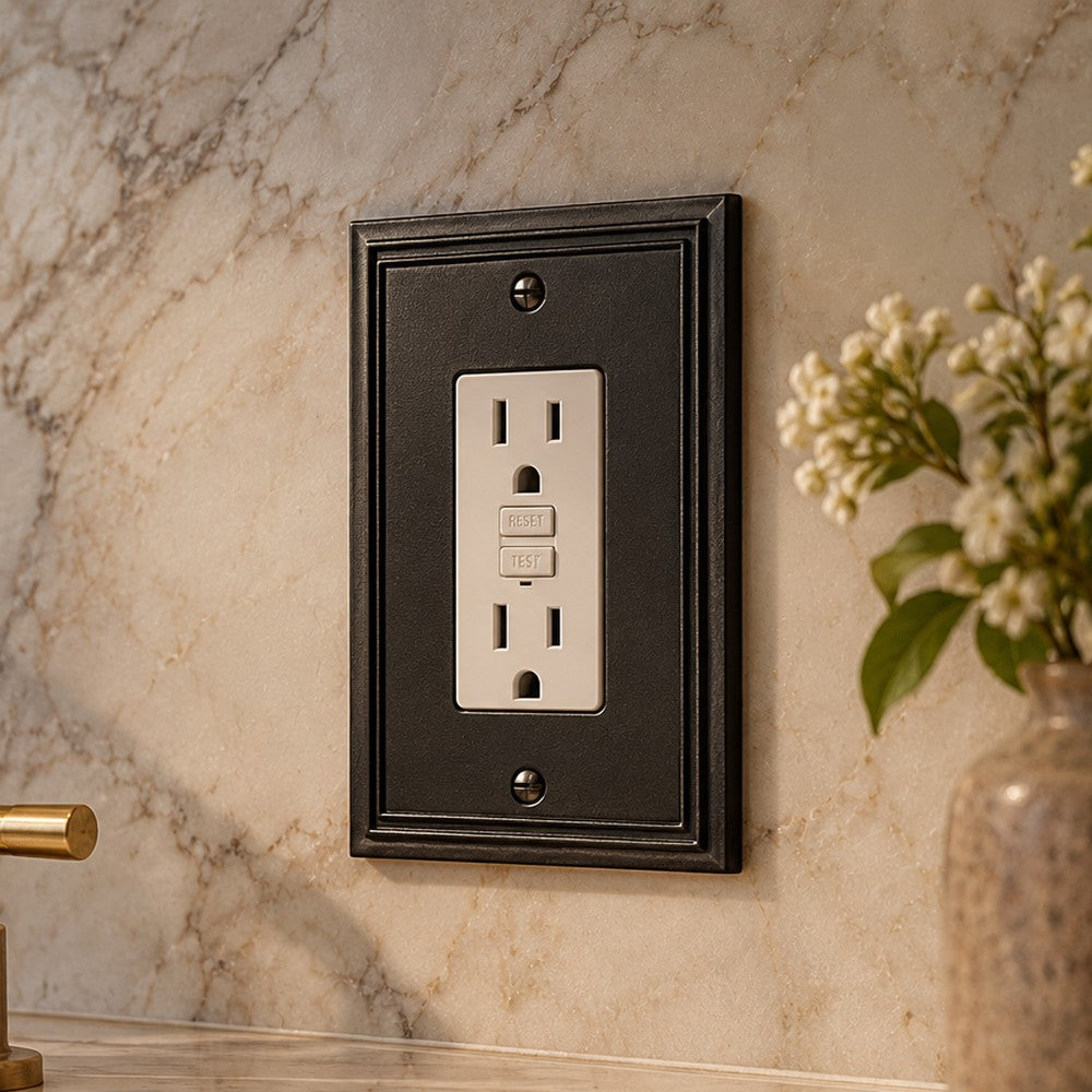 Imperial Black rocker plate around a GFCI outlet on a marble backsplash.