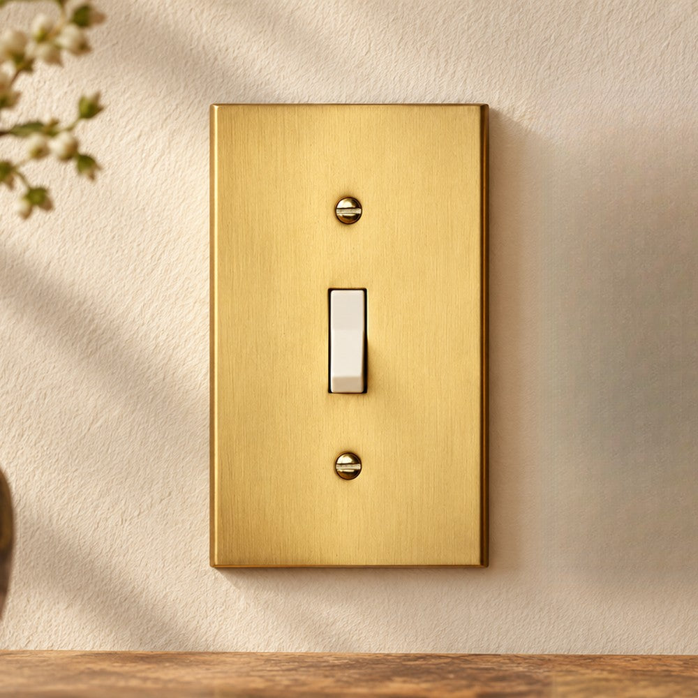 Brushed gold toggle switch plate on a warm white wall.