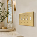 Deco 4G Toggle wall plate in Brushed Brass on a wall in a styled room