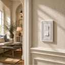 Estate 1-gang rocker switch plate in White on a light wall in a living room hallway with arched doorways