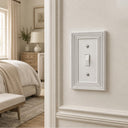Estate 1-gang toggle switch plate in White on a light wall in a bedroom with wainscoting