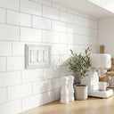 Estate 3-gang rocker switch plate in White on a light wall in a kitchen with white subway tile