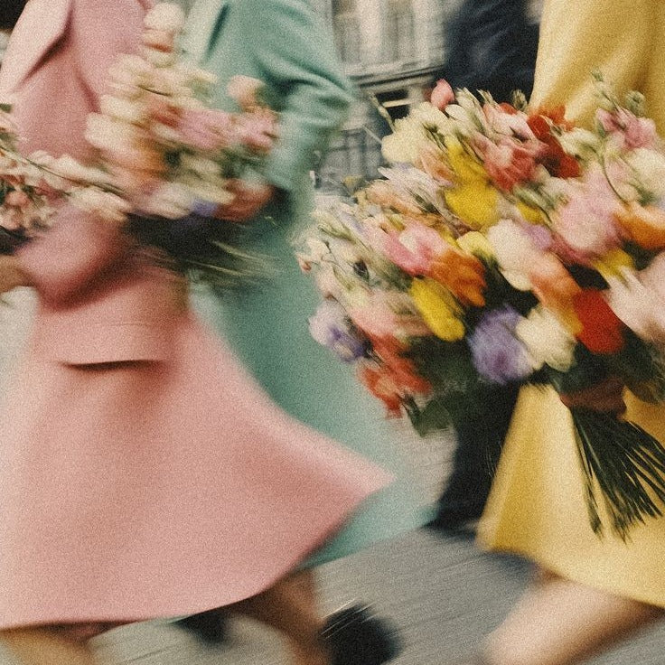 Women in pastel coats carrying flower bouquets