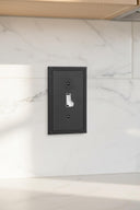 Imperial 1G Toggle wall plate in Black on a wall in a styled room