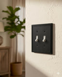 Imperial 2G Toggle wall plate in Black on a wall in a styled room