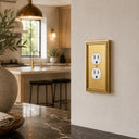 Imperial 1G Duplex wall plate in Brushed Gold on a wall in a styled room