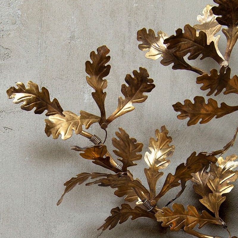 Gilded leaf branch on a pale wall