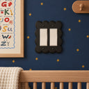 Scallop 2G Rocker switch plate in Black on navy star wallpaper above a wooden crib in a nursery