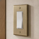 Signature 1-gang rocker switch plate in Aged Gold installed on a wall