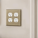Signature 2-gang duplex outlet cover in Aged Gold installed on a wall