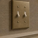 Signature 2-gang toggle switch plate in Aged Gold installed on a wall