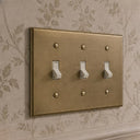Signature 3-gang toggle switch plate in Aged Gold, room setting