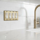 Signature 4-gang rocker switch plate in Aged Gold installed on a wall