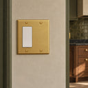 Signature 2G Blank Rocker combo wall plate in Brushed Brass on a warm plaster wall